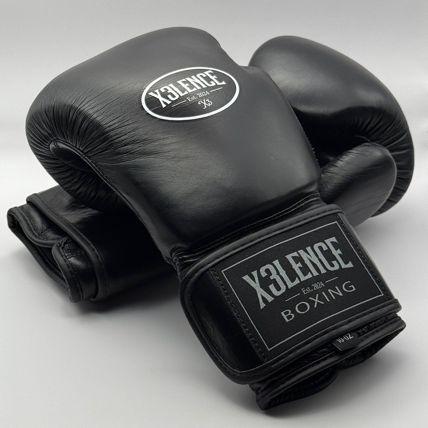 Set van zwarte X3LENCE bokshandschoenen in echt leer – stijlvol en professioneel design met stevig klittenbandsluiting, ideaal voor zowel beginners als gevorderde boksers. Beschikbaar in 10, 12, 14 en 16 oz voor elke trainingsbehoefte.