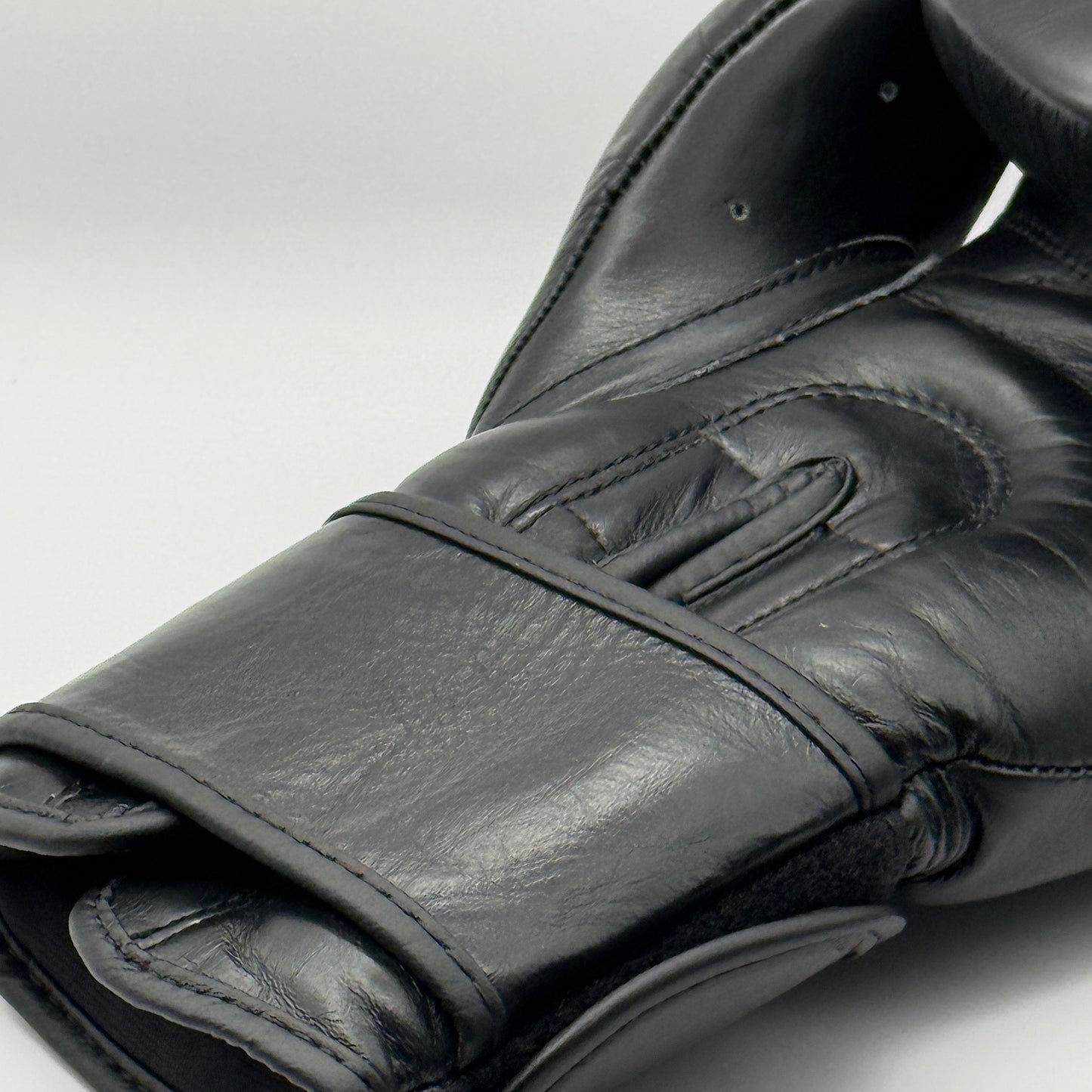 Detail van de binnenkant van een zwarte X3LENCE bokshandschoen – handgemaakt van echt leer met ergonomische stiknaden en stevige polssteun voor optimale pasvorm en bescherming.