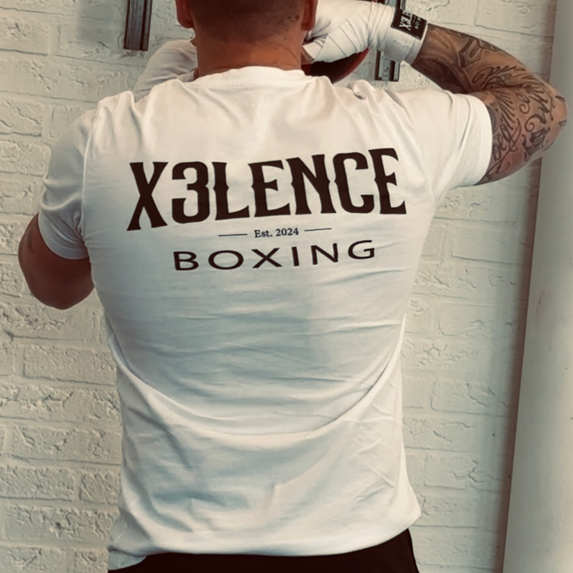 Wit X3LENCE Boxing T-shirt gedragen door sporter met bokshandschoenen, zwart logo op de rug