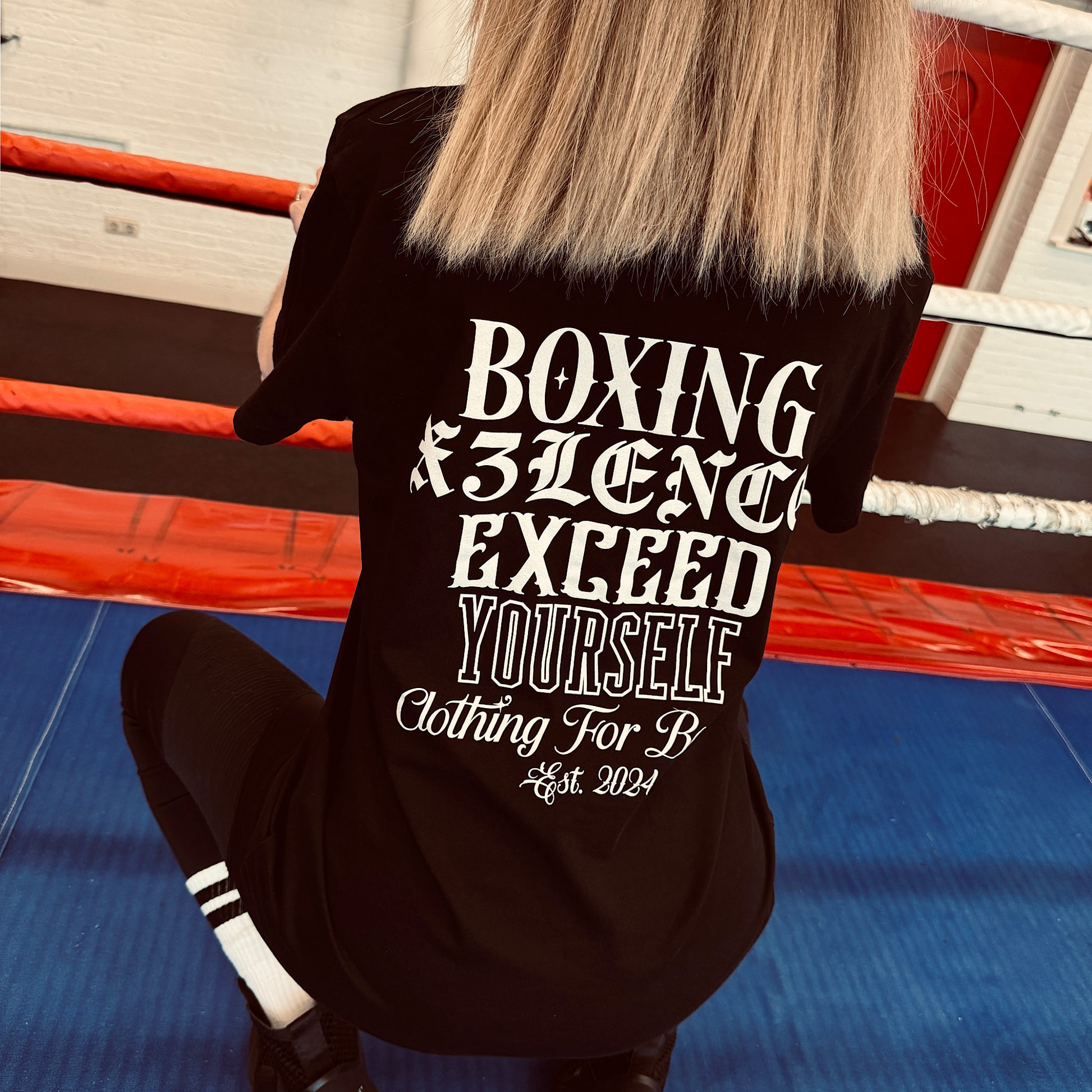 Draagster van zwart X3LENCE t-shirt met opvallende rugprint “Exceed Yourself”, ideaal voor bokstraining of streetwear